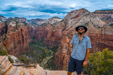 Naklejka premium A young man enjoying the views of Zion from the Angels Landing Trail in Zion National Park, Utah. United States.