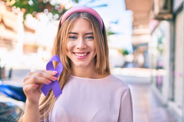 Young caucasian girl smiling happy holding purple ribbon walking at the city.