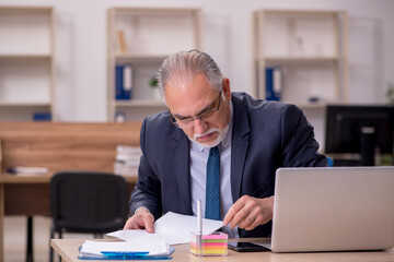 Old businessman employee sitting at workplace