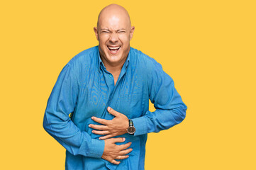 Middle age bald man wearing casual clothes smiling and laughing hard out loud because funny crazy joke with hands on body.