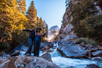 A couple in the first rays of sunrise at Vernal Falls in Yosemite National Park and a tourist on a...