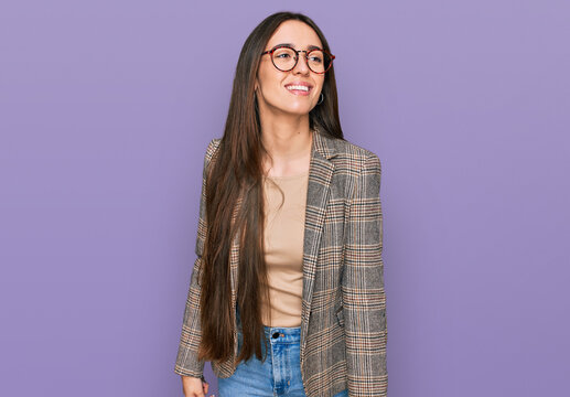 Young hispanic girl wearing business clothes and glasses looking away to side with smile on face, natural expression. laughing confident.