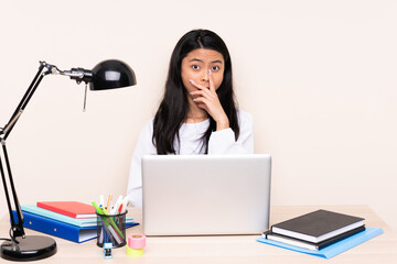 Student asian girl in a workplace with a laptop isolated on beige background surprised and shocked while looking right