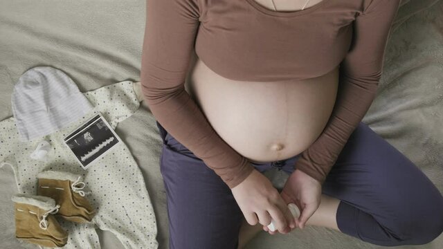 expecting pregnant woman with big belly sits on couch at home, takes medicine