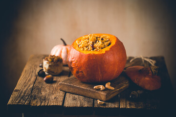 Tasty baked pumpkin stuffed with rice, vegetables, cashews and dried fruits on wooden table with...