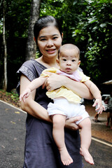 Fototapeta premium Asian 35s mother is holding and kissing her toddler's cheek in her hand , mother smile and happy .Selective focus at face mother ,family and motherhood concept. 