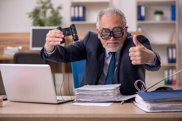 Old male employee auditor wearing many glasses at workplace