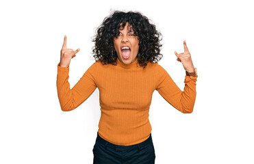 Young hispanic woman wearing casual clothes shouting with crazy expression doing rock symbol with hands up. music star. heavy music concept.