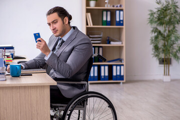 Young male enployee in wheel-chair at workplace