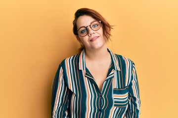Young caucasian woman wearing casual clothes and glasses relaxed with serious expression on face....