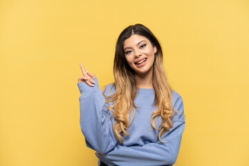 Young Russian girl isolated on yellow background pointing up a great idea