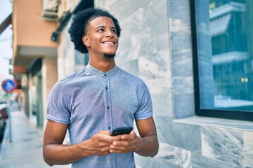 Young african american man smiling happy using smartphone at the city.