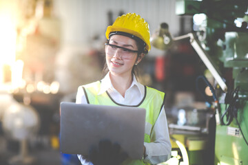 Woman worker wearing safety goggles control lathe machine to drill components. Metal lathe industrial manufacturing factory