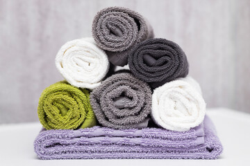 Obraz na płótnie Canvas Rolled cotton fluffy towels of different colors in the bathroom on a white surface.