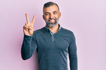 Middle age handsome man wearing casual clothes showing and pointing up with fingers number two while smiling confident and happy.