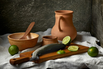 Still life in a rustic style. Set of ceramic dishes, fresh fish and a bread on a wooden table.