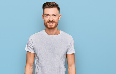 Young redhead man wearing casual grey t shirt with a happy and cool smile on face. lucky person.