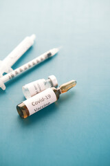 Close up of coronavirus vaccine and syringe on green background