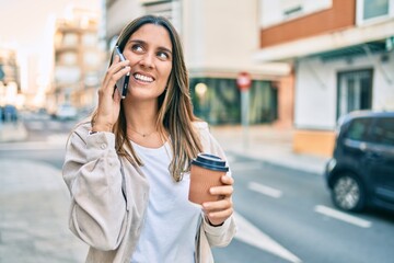 Young caucasian woman smiling happy talking on the smartphone and drinking take away coffee at the city.
