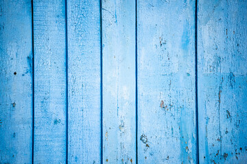 Aged blue and green planks with peeled paint. Blue background. Close-up. Copy space. Defocus.