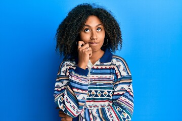 Fototapeta na wymiar Beautiful african american woman with afro hair wearing casual clothes thinking concentrated about doubt with finger on chin and looking up wondering