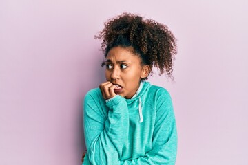 Fototapeta na wymiar Beautiful african american woman with afro hair wearing casual sweatshirt looking stressed and nervous with hands on mouth biting nails. anxiety problem.
