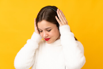 Teenager girl isolated on yellow background listening music