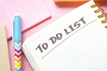 To do list in notebook with office suppliers on desk.