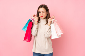 Teenager girl isolated on pink background holding shopping bags and smiling