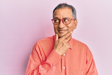 Obraz premium Middle age indian man wearing casual clothes and glasses with hand on chin thinking about question, pensive expression. smiling with thoughtful face. doubt concept.