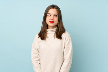 Obraz premium Teenager girl isolated on blue background laughing and looking up