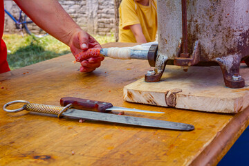 Butcher is stuffing pig intestine with minced meat to make sausages.