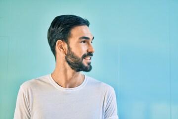 Young hispanic man smiling happy standing at the city.