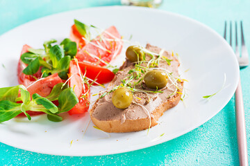 Fresh homemade chicken liver pate on bread and tomatoes salad. Breakfast.