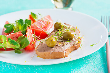 Fresh homemade chicken liver pate on bread and tomatoes salad. Breakfast.