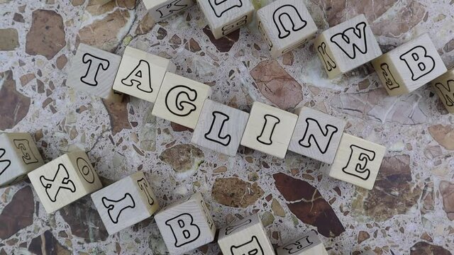 Tagline concept with the word on wood blocks and upper and lower borders of wooden cubes with random letters over a marbled stone background. Rotating table