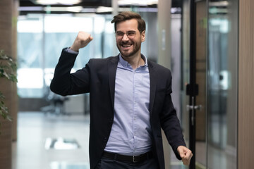 Overjoyed young Caucasian male employee have fun or party in office excited with good results or promotion. Happy man worker dance celebrate job success or work achievement. Luck concept.