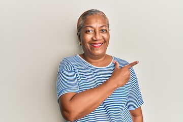 Senior african american woman wearing casual clothes smiling cheerful pointing with hand and finger up to the side - Powered by Adobe
