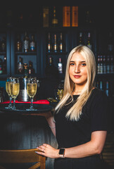 Girl waiter with sparkling wine glasses in a bar or restaurant