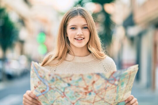 Beautiful caucasian tourist teenager smiling happy holding map at the city.