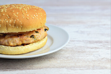 Homemade meat burger with vegetables, mushrooms and a touch of spinach. Served on a small white plate, wooden base. Copy space.