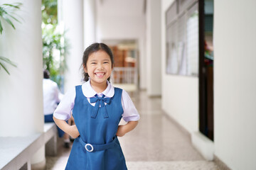 Asian child cute or kid girl smiling broken tooth and student wearing blue school uniform with friend and raised hand on waist to happy at primary or elementary education and back to school with space