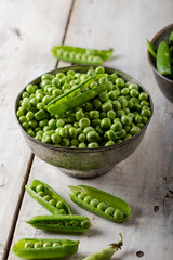 Fresh green peas. Fresh green peas pods and green peas in the bowl on wooden background.