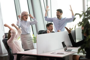 Excited diverse multiethnic businesspeople scream celebrate company business achievement in office. Overjoyed multiracial colleagues coworkers feel euphoric with win or victory. Success concept.