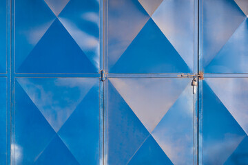 Fototapeta na wymiar Light reflection on rhombus pattern surface of the old steel folding gate door of machine shop