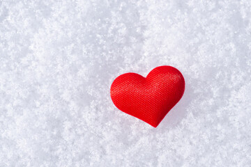 One small red heart on fluffy snow. Symbol of love