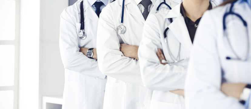 Group of modern doctors standing as a team with arms crossed in hospital office. Medical help, insurance in health care, best desease treatment and medicine concept