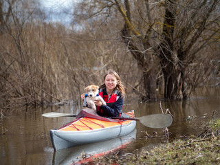 A girl and a little puppy are sailing on a kayak