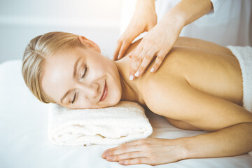 Happy woman enjoying back massage with closed eyes. Beauty and Spa salon concept