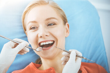Happy woman is being examined by dentist at dental clinic. Healthy teeth and medicine, stomatology concept